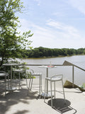 muuto steel linear bar stool in white on a patio overlooking a lake