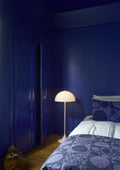 Louis Poulsen Panthella 400 Floor Lamp, white opal acrylic floor lamp, lit beside a bed in a deep blue bedroom