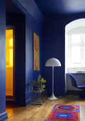 Louis Poulsen Panthella Floor Lamp, white opal acrylic floor lamp in a deep blue room beside a window desk and a potted plant