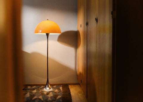 Louis Poulsen Panthella Floor Lamp, Original Opal Orange floor lamp, lit in a corner beside wooden wardrobe doors
