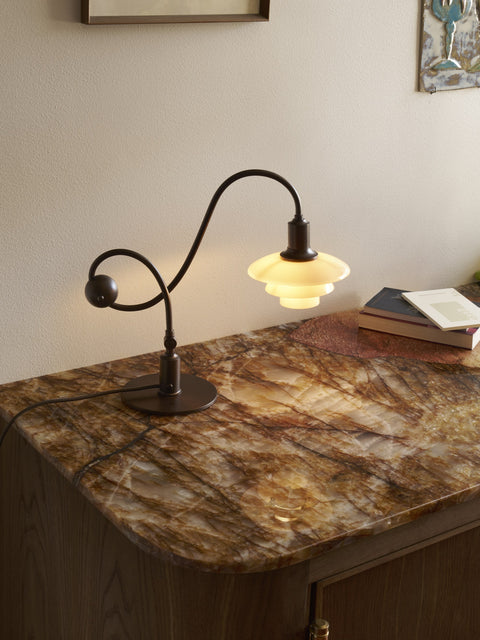 Louis Poulsen PH 1/1 Piano Table Lamp, Limited Edition, lit on a stone-topped wooden cabinet beside a stack of books