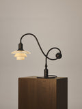 Louis Poulsen PH 1/1 Piano Table Lamp, Limited Edition, lit on a dark wood plinth, showing the curved stem and round counterweight