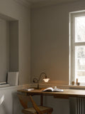 Louis Poulsen PH 1/1 Piano Table Lamp, Limited Edition, lit on a wooden desk beside a window in a grey room