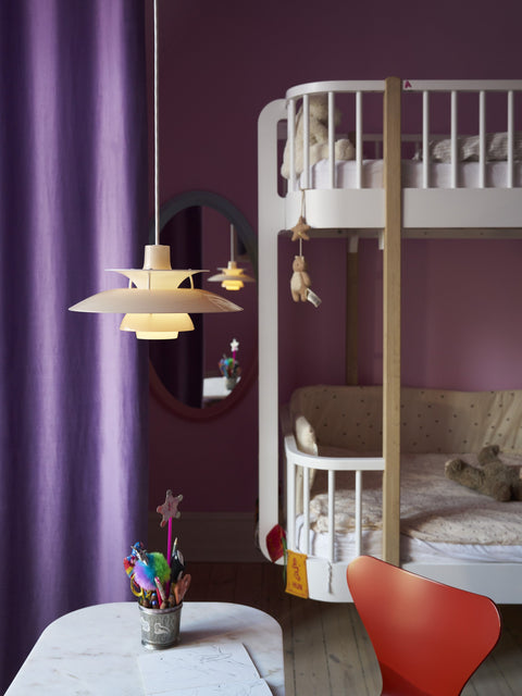 Louis Poulsen PH 5 Opal pendant light in Opal Beige, lit above a marble table and red chair in a children's room with purple curtains