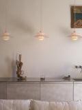 Three Louis Poulsen PH 5 Opal pendant lights in Opal Pale Rose, lit in a row above a steel kitchen counter against a pale wall