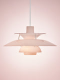 Louis Poulsen PH 5 Opal pendant light in Opal Pale Rose, lit against a soft pink backdrop, showing the glossy stepped shades