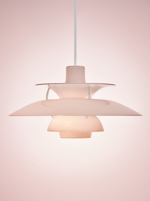 Louis Poulsen PH 5 Opal pendant light in Opal Pale Rose, lit against a soft pink backdrop, showing the glossy stepped shades