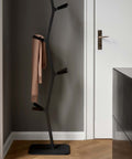 sculptural coat stand in black lacquered finish in an entryway designed by shin azumi for fredericia furniture