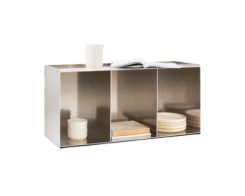 Frama Rivet Case in Aluminum, angled view of the case with candles, a bowl, books and stacked plates filling its bays