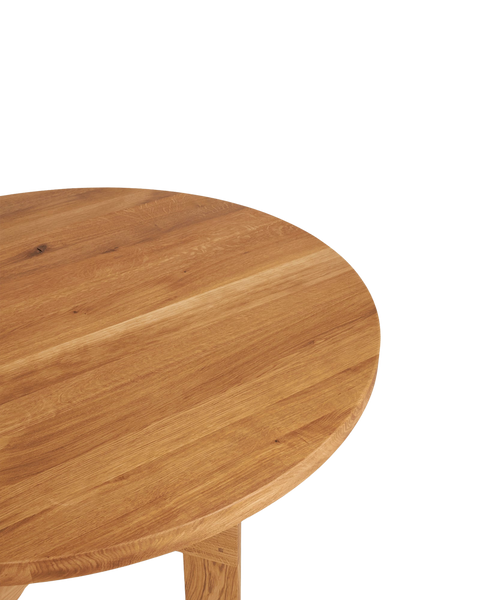Frama Farmhouse Trestle Table in Natural Oak, crop of the round oak top showing the grain and the eased edge above a leg