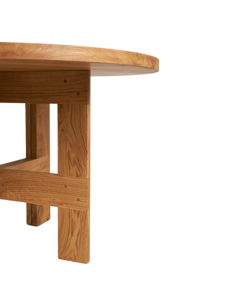 Frama Farmhouse Trestle Table in Natural Oak, close view of a trestle leg meeting the underside of the round top at a pegged joint
