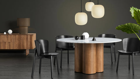 Blu Dot 4/4 Round Dining Table 60-inch with marble top and walnut base in a dark moody dining room

