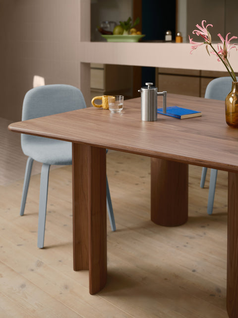 Muuto Re Norm Table 130 in walnut veneer with light blue upholstered chairs in contemporary dining room