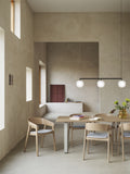 Muuto Rime Rail Lamp in black rail version above modern Scandinavian dining table with oak chairs