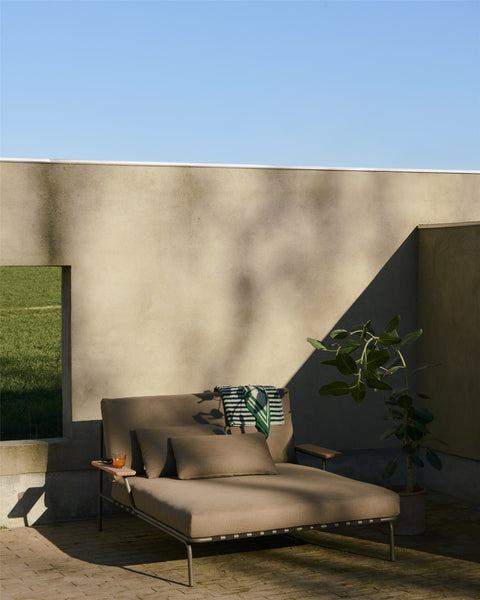 Scandinavian outdoor scene featuring Muuto Settle Lounge Bed with Armrest in taupe, minimalist design for patio or terrace