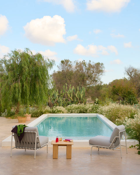 Muuto Settle lounge chairs in grey with teak Assemble coffee table facing swimming pool