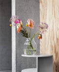 Serene home decor scene with Muuto Silent Vase in Glass holding simple greenery, surrounded by soft textures.