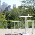 Skiff 30" Outdoor Bar Height Table by Blu Dot in white, styled on outdoor terrace with Skiff Outdoor Bar Stools