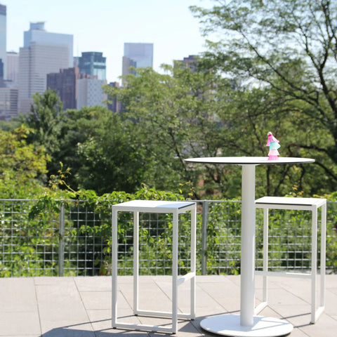 Skiff 30" Outdoor Bar Height Table by Blu Dot in white, styled on outdoor terrace with Skiff Outdoor Bar Stools