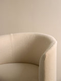 Audo Copenhagen Tearoom Chair, With Loose Cover, close-up of the Tearoom Club Chair, showing the texture and curve of its off-white loose cover against a beige wall