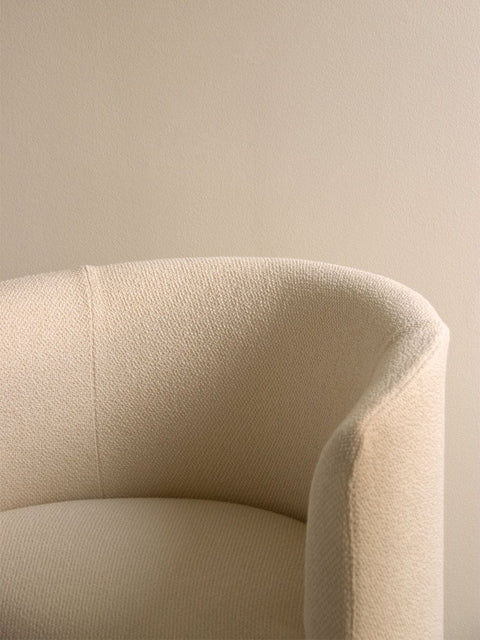 Audo Copenhagen Tearoom Chair, With Loose Cover, close-up of the Tearoom Club Chair, showing the texture and curve of its off-white loose cover against a beige wall