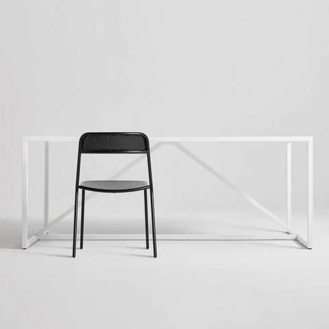 Trim Chair by Blu Dot in Black perforated powder-coated steel, front view with Strut dining table