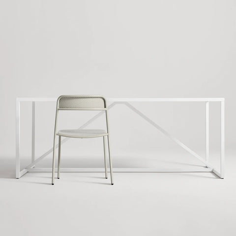 Trim Chair by Blu Dot in Putty perforated powder-coated steel, front view with Strut dining table