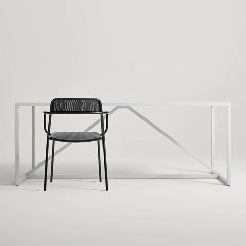 Trim Armchair by Blu Dot in Black perforated powder-coated steel, front view with Strut dining table