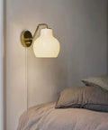 brass and opal glass wall lamp in a bedroom