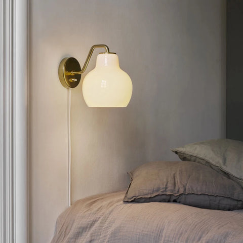 brass and opal glass wall lamp in a bedroom