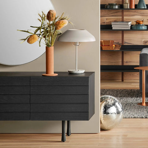 Blu Dot Beau Table Lamp in putty styled on a dark credenza in a modern living room setting
