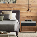 Blu Dot Construct Nightstand in Carrara marble top and black powder-coated steel frame, styled in a modern bedroom beside a grey upholstered bed with a vintage stereo receiver on top and amber glass pendant light above